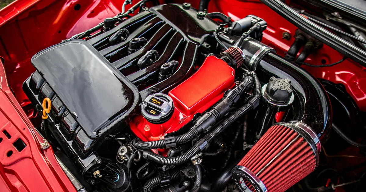 Close-up of a car engine featuring a red and black color scheme with open hood.