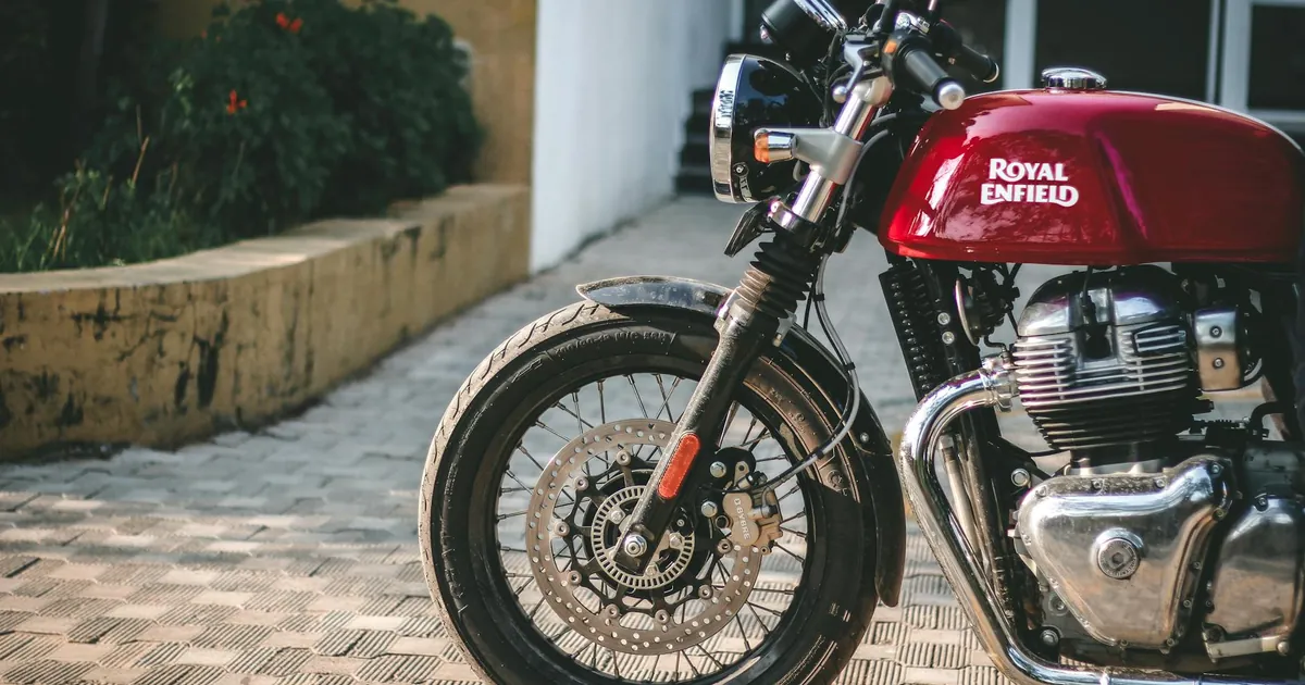 A detailed shot of a Royal Enfield motorcycle parked outdoors, showcasing its front wheel and engine.