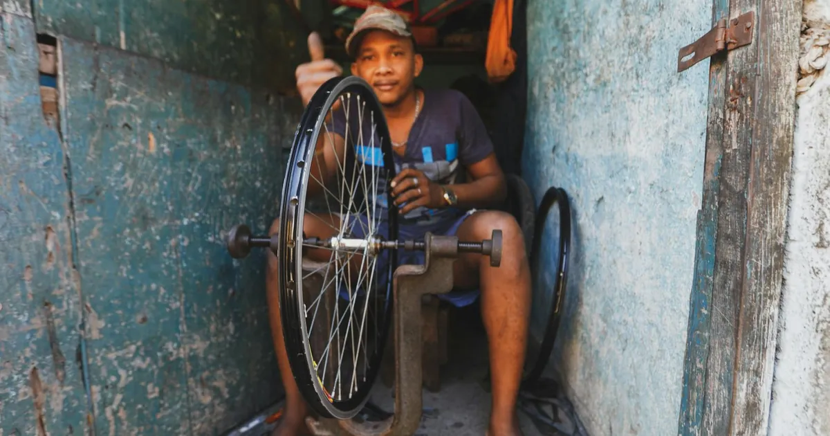A skilled repairman fixing a bicycle wheel in his workshop, surrounded by tools and equipment.