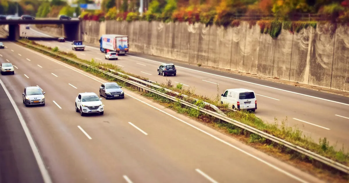 Cars and trucks moving on a highway under sunny skies, showcasing road travel.