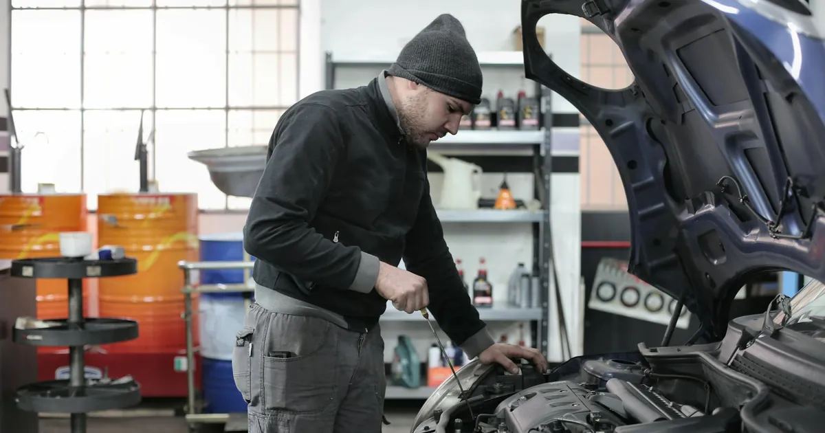 Mechanic checking a car engine in a garage, ensuring quality maintenance and repair.