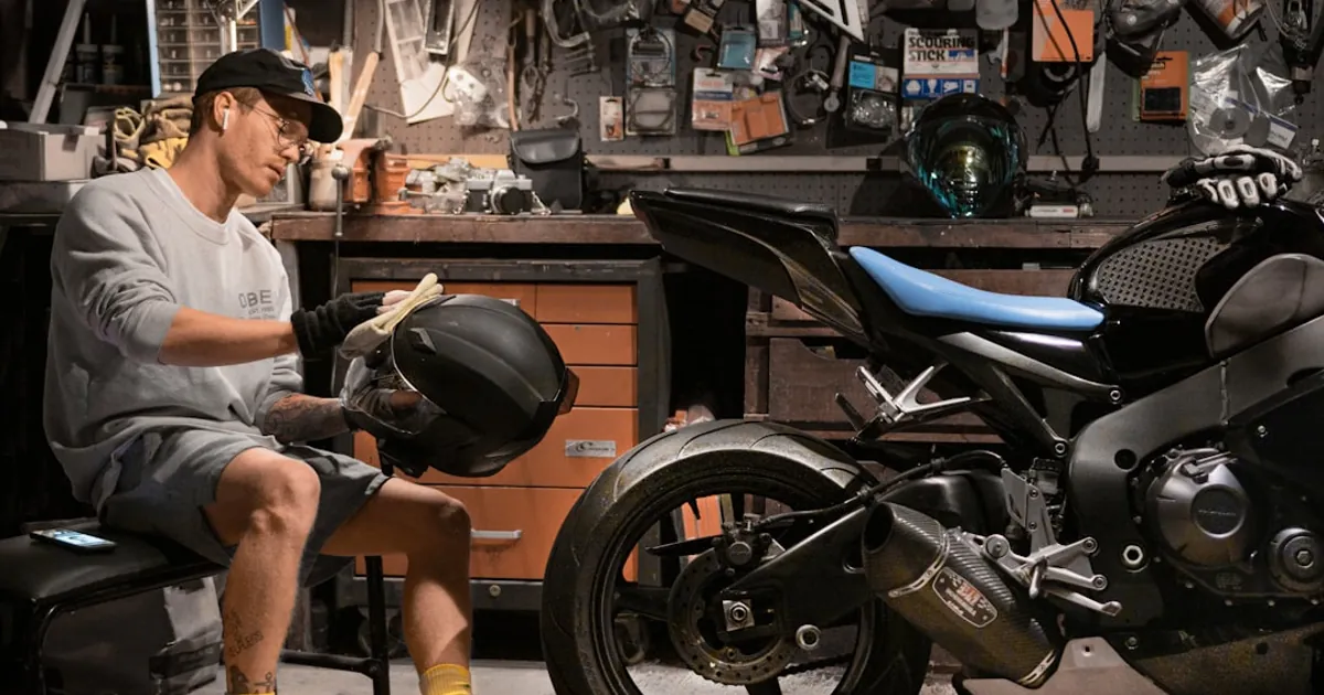 man wiping motorcycle helmet by motorcycle