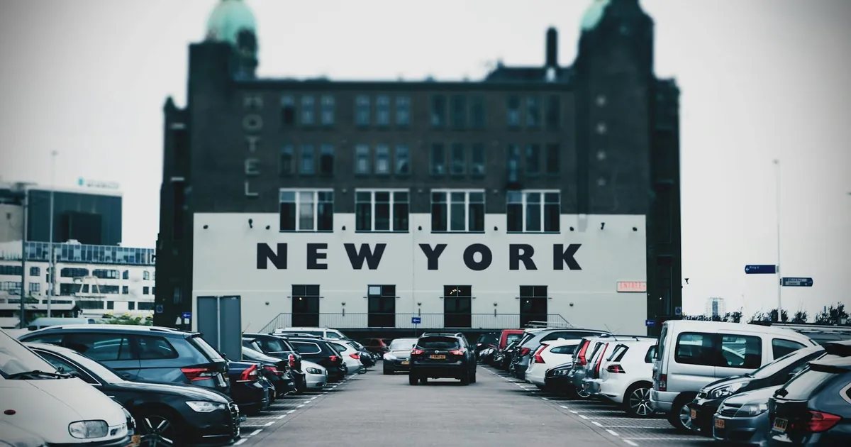 View of a parking lot with cars and a building featuring bold New York text.
