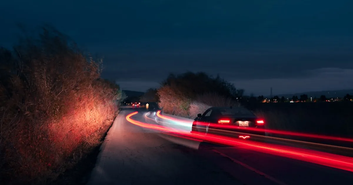 Cars driving on a road at night with light trails