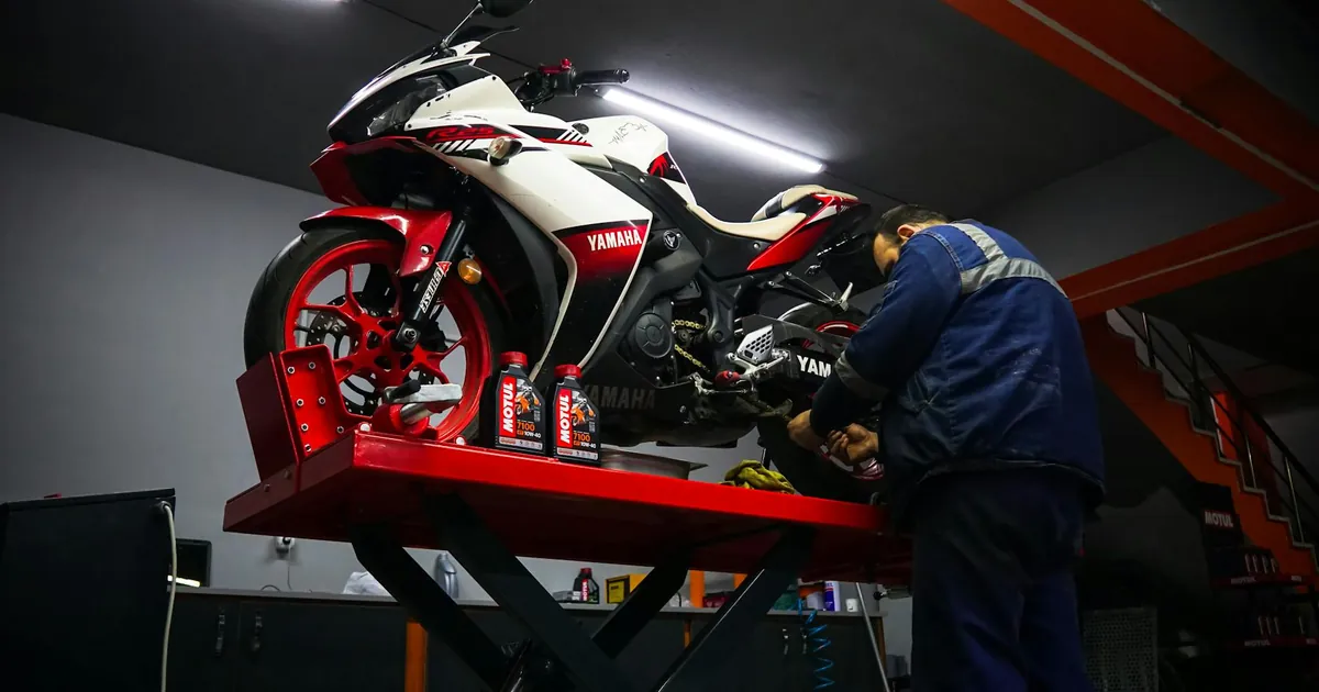 Auto mechanic repairing a Yamaha motorbike in a garage.