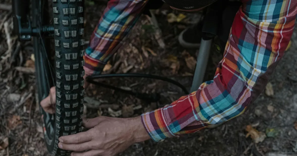 Man adjusting a bicycle tire outdoors, focusing on maintenance work.
