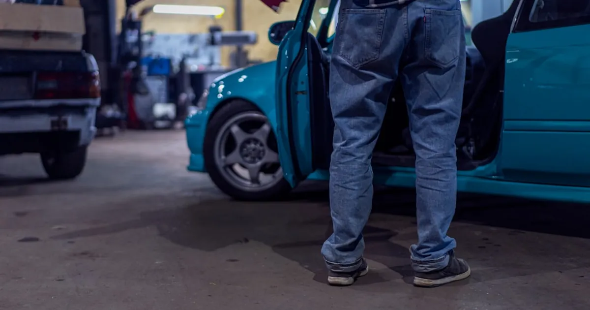 man in blue denim jeans and black leather boots standing beside blue car during daytime