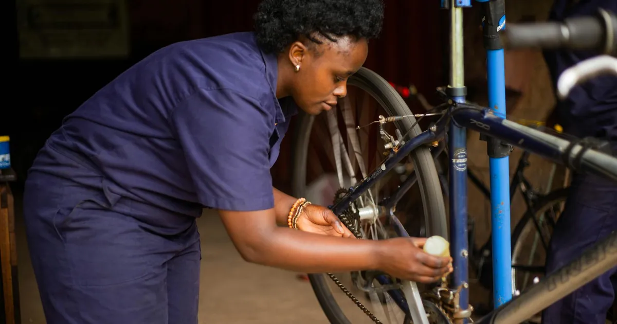 Adult female mechanic meticulously repairing a bicycle in a workshop setting.