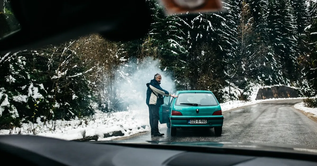 man standing in front of teal vehicle hatchback