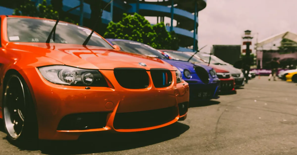 Close-up of vibrant sports cars parked outdoors, showcasing custom modifications and sleek designs.